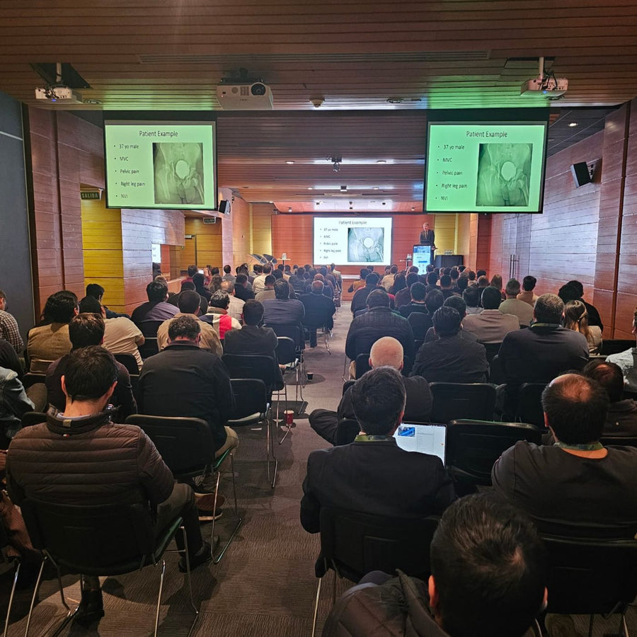 Auditorio lleno de asistentes siguiendo una presentación de caso clínico durante el curso de fracturas de cadera en Clínica Las Condes